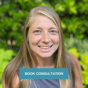Ashley Bristow, landscape designer, smiles in front of green shrubs